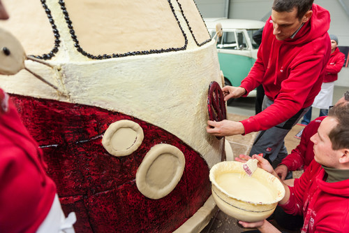 Helfer kleben mit weißer Schokolade das VW-Logo auf den Lebkuchen-Bulli.
