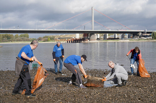 Ausgerüstet mit Greifzangen und recycelbaren Müllsäcken räumen Ford-Beschäftigte am Rheinufer vor der Leverkusener Brücke auf. 