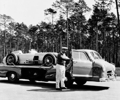 Der mehrfache Weltmeister Juan Manuel Fangio und der Mercedes-Benz Renntransporter &quot;Das blaue Wunder“ mit einem Formel-1-Rennwagen W 196 R auf der Ladefläche.