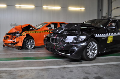 Der neue BMW 5er im Crash, beide Male mit 64 km/h Anfahrgeschwindigkeit: im Vordergrund ein Fahrzeug, das vor dem Aufprall automatisch auf 40 km/h abgebremst wurde, dahinter ein ungebremst aufgefahrenes Exemplar.