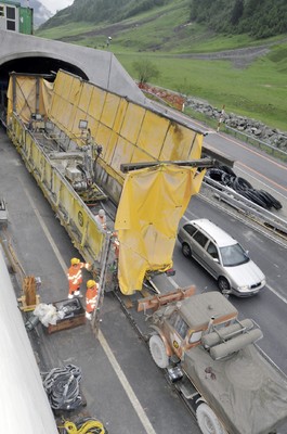 Der Unimog schiebt Baumaschinen auf Schienen durch Alpentunnel in der Schweiz.