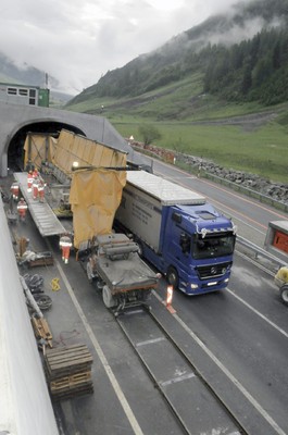 Der Unimog schiebt Baumaschinen auf Schienen durch Alpentunnel in der Schweiz.