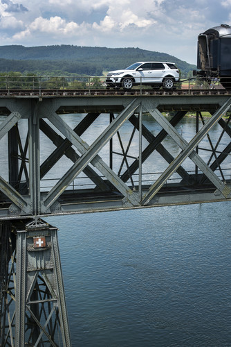 Ein Land Rover Discovery Sport zieht drei historische Eisenbahnwaggons mit über 100 Tonnen Gesamtgewicht über den Rhein.