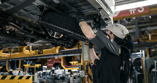 Eine Mitarbeiterin in der Nissan-Produktion testet ein Exoskelett.