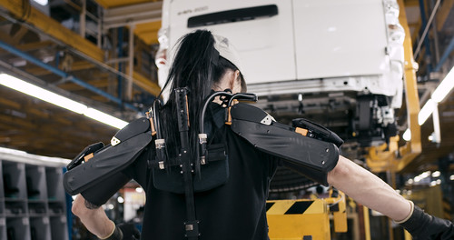 Eine Mitarbeiterin in der Nissan-Produktion testet ein Exoskelett.