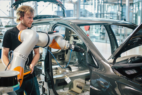 Software Development Center von Volkswagen in Dresden: Ein Roboter trägt den Primer für die Verklebung der Seitenscheibe auf, anschließend führt ein Kamerasystem die optische Qualitätskontrolle durch.
