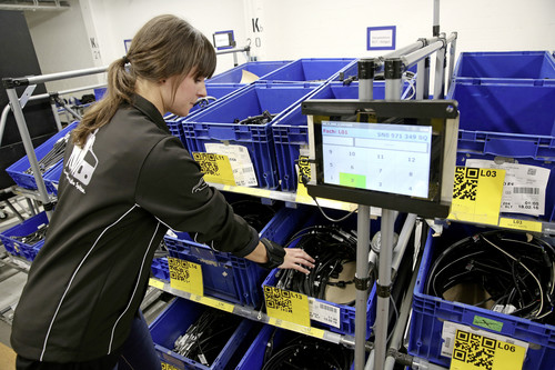 Volkswagen-Mitarbeiterin Isabell Pfeiffer kommissioniert Material mit Hilfe eines RFID-Armbands.