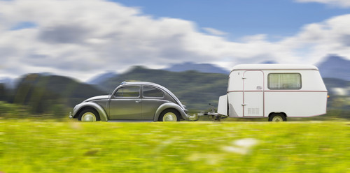 VW Käfer mit Wohnwagenanhänger.