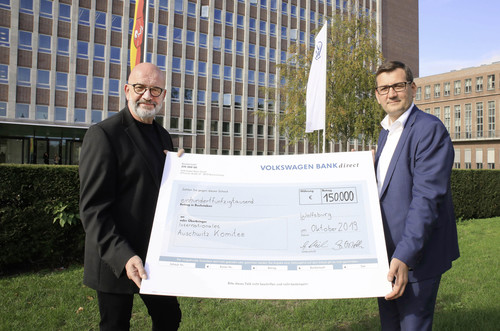 VW-Personalvorstand, Gunnar Kilian (re), und der Vorsitzende des Konzernbetriebsrats, Bernd Osterloh, unterzeichnen einen symbolischen Spendenscheck für Auschwitz heute in Wolfsburg.