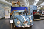 Hans Wehner (90) am Duplikat seines damals neuen 34-PS-Käfers. Darüber ist das Werbeplakat zu sehen, mit dem Volkswagen den Sieg Wehners bei der Tour d’Europe gewürdigt hat.
